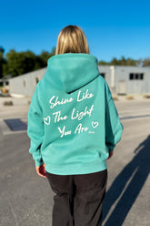Moderner, oversized Unisex-Hoodie in Turquoise Green aus kuschlig weicher Baumwolle mit einem Print auf der Rückseite.