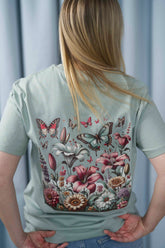T-Shirt aus 100 % Bio-Baumwolle mit normaler Passform, erhältlich in verschiedenen Farben wie Blue Soul, Cotton Pink, Lavender, Aloe, Weiss und Schwarz. Individuell bedruckbar mit Wunschmotiv. Weiches, angenehm leichtes Material für hohen Tragekomfort. Ideal für einen zeitgemässen, entspannten Look. Vorderseite: Farbiger Schmetterling auf der linken Brust. Rückseite: Buntes Blumen- und Schmetterlingsfeld im Illustrationsstil.