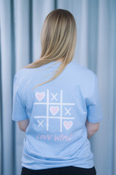 T-Shirt aus 100 % Bio-Baumwolle mit normaler Passform, erhältlich in verschiedenen Farben wie Blue Soul, Cotton Pink, Lavender, Aloe, Weiss und Schwarz. Individuell bedruckbar mit Wunschmotiv. Weiches, angenehm leichtes Material für hohen Tragekomfort. Ideal für einen zeitgemässen, entspannten Look. Vorderseite: Rosa Herz auf der linken Brust. Rückseite: Tic-Tac-Toe-Motiv mit rosa Herzen und darunter der Schriftzug „LOVE WINS“ in rosa.