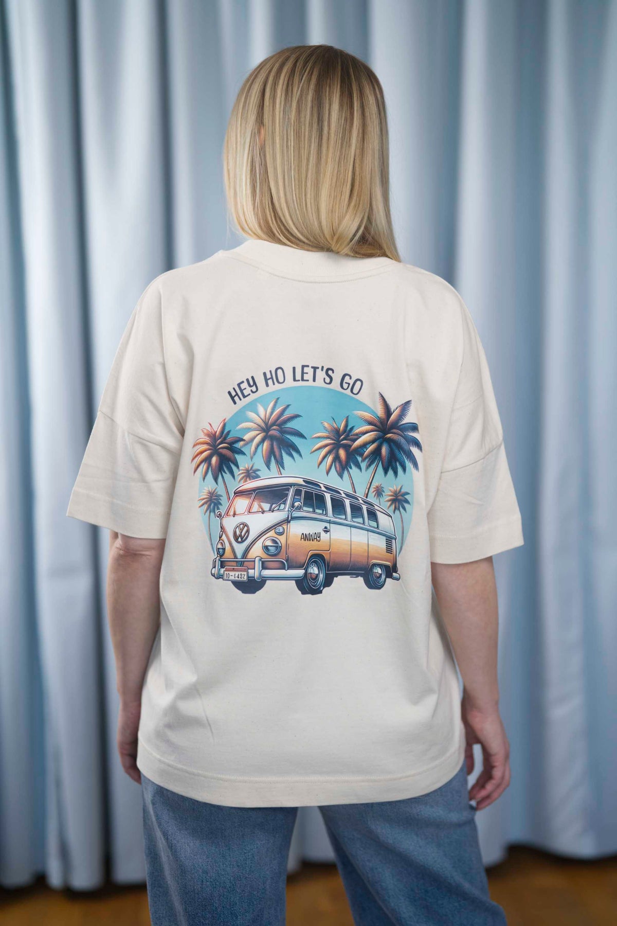 Oversized T-Shirt aus 100 % Bio-Baumwolle mit weitem, modernem Schnitt, erhältlich in Schwarz, Weiss und Natur. Individuell gestaltbar mit Wunschmotiv und frei wählbarer Platzierung. Weiche Qualität, überschnittene Ärmelansätze und lässiger Style für maximalen Tragekomfort. Mit Retro-Bus-Print, Palmen und „HEY HO LET'S GO“-Schriftzug.