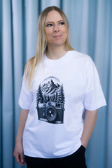Oversized T-Shirt aus 100 % Bio-Baumwolle mit weitem, modernem Schnitt, erhältlich in Schwarz, Weiss und Natur. Individuell gestaltbar mit Wunschmotiv und frei wählbarer Platzierung. Weiche Qualität, überschnittene Ärmelansätze und lässiger Style für maximalen Tragekomfort. Mit retro Kamera-Illustration, Bergpanorama und Tannenwäldern auf der Brust.