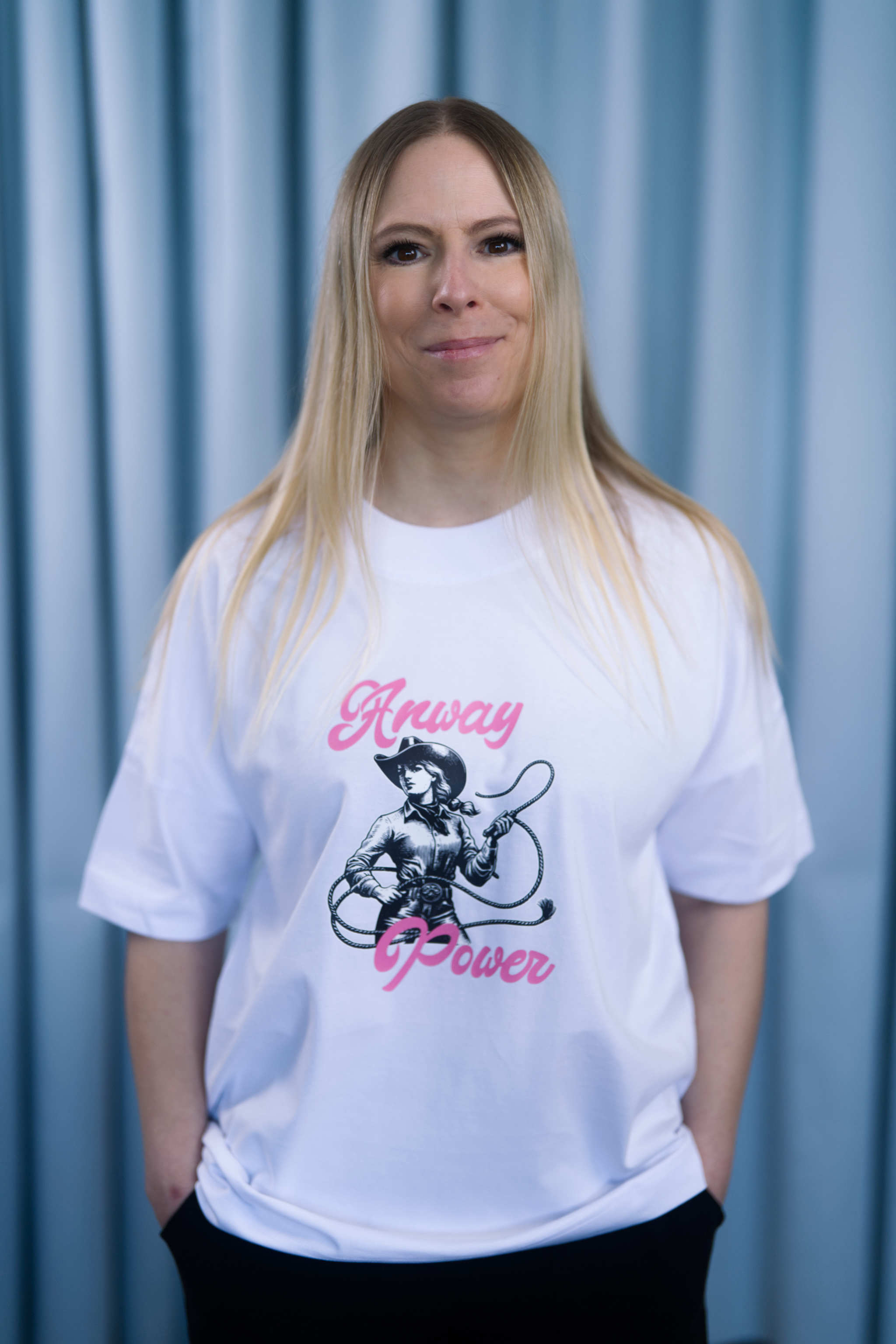 Oversized T-Shirt aus 100 % Bio-Baumwolle mit weitem, modernem Schnitt, erhältlich in Schwarz, Weiss und Natur. Individuell gestaltbar mit Wunschmotiv und frei wählbarer Platzierung. Weiche Qualität, überschnittene Ärmelansätze und lässiger Style für maximalen Tragekomfort.  T-Shirt mit einer Cowgirl-Illustration mit Peitsche und dem rosa Schriftzug „Anway Power“ auf der Vorderseite.