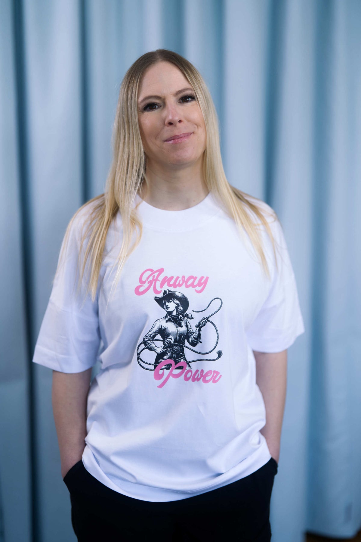 Oversized T-Shirt aus 100 % Bio-Baumwolle mit weitem, modernem Schnitt, erhältlich in Schwarz, Weiss und Natur. Individuell gestaltbar mit Wunschmotiv und frei wählbarer Platzierung. Weiche Qualität, überschnittene Ärmelansätze und lässiger Style für maximalen Tragekomfort.  T-Shirt mit einer Cowgirl-Illustration mit Peitsche und dem rosa Schriftzug „Anway Power“ auf der Vorderseite.