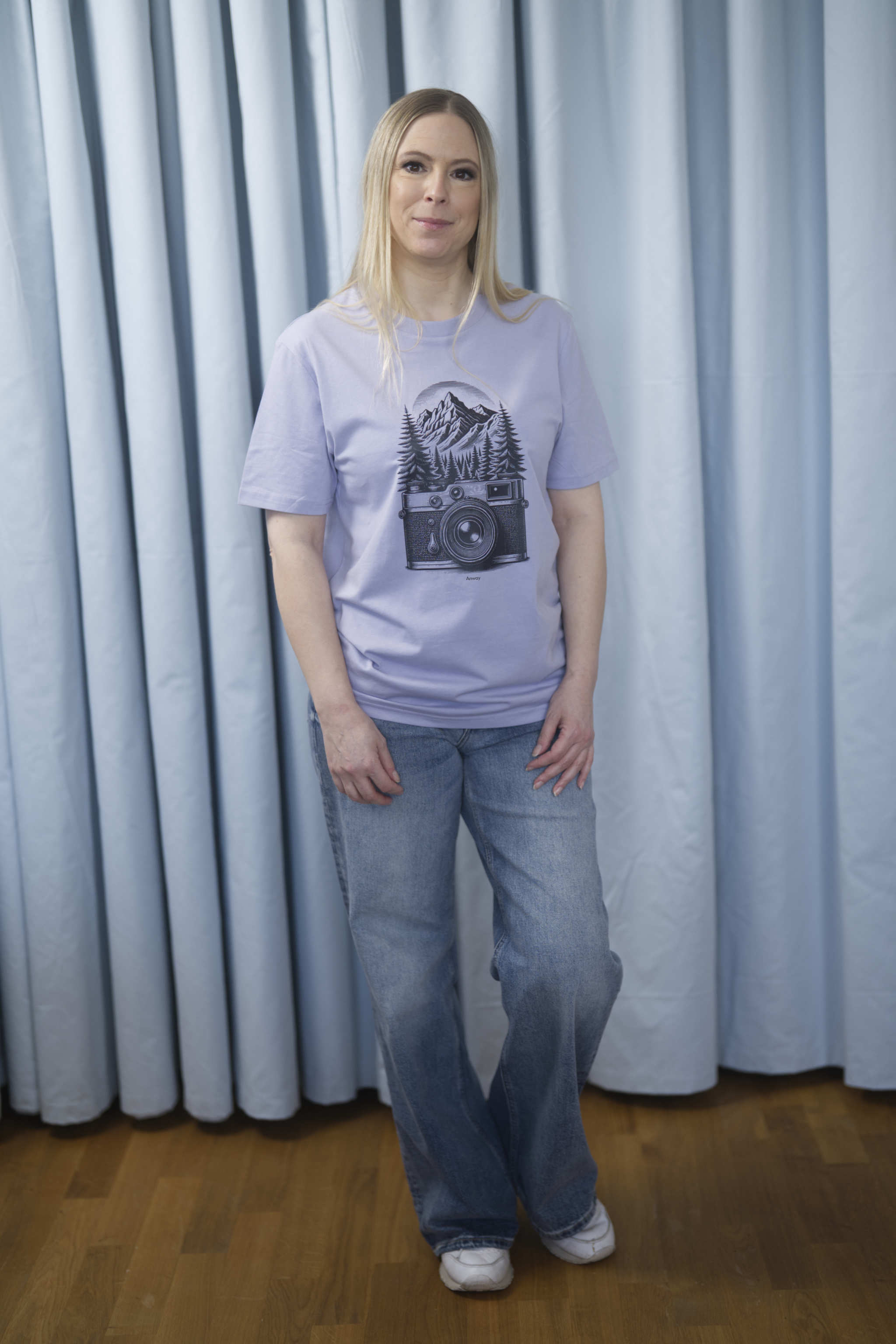 T-Shirt aus 100 % Bio-Baumwolle mit normaler Passform, erhältlich in verschiedenen Farben wie Blue Soul, Cotton Pink, Lavender, Aloe, Weiss und Schwarz. Individuell bedruckbar mit Wunschmotiv. Weiches, angenehm leichtes Material für hohen Tragekomfort. Ideal für einen zeitgemässen, entspannten Look. Mit schwarzer Kamera-Illustration, Bergpanorama und Tannenwäldern auf der Vorderseite des T-Shirts.