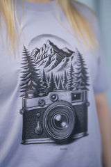 T-Shirt aus 100 % Bio-Baumwolle mit normaler Passform, erhältlich in verschiedenen Farben wie Blue Soul, Cotton Pink, Lavender, Aloe, Weiss und Schwarz. Individuell bedruckbar mit Wunschmotiv. Weiches, angenehm leichtes Material für hohen Tragekomfort. Ideal für einen zeitgemässen, entspannten Look. Mit schwarzer Kamera-Illustration, Bergpanorama und Tannenwäldern auf der Vorderseite des T-Shirts.