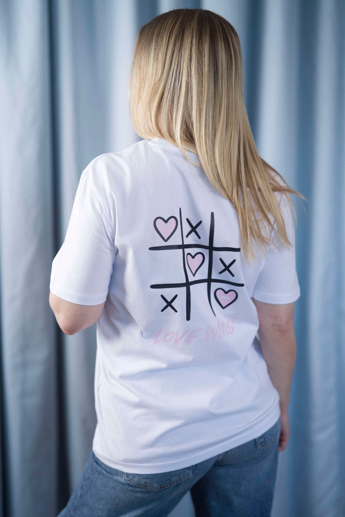T-Shirt aus 100 % Bio-Baumwolle mit normaler Passform, erhältlich in verschiedenen Farben wie Blue Soul, Cotton Pink, Lavender, Aloe, Weiss und Schwarz. Individuell bedruckbar mit Wunschmotiv. Weiches, angenehm leichtes Material für hohen Tragekomfort. Ideal für einen zeitgemässen, entspannten Look. Vorderseite: Rosa Herz auf der linken Brust. Rückseite: Tic-Tac-Toe-Motiv mit rosa Herzen und darunter der Schriftzug „LOVE WINS“ in rosa.