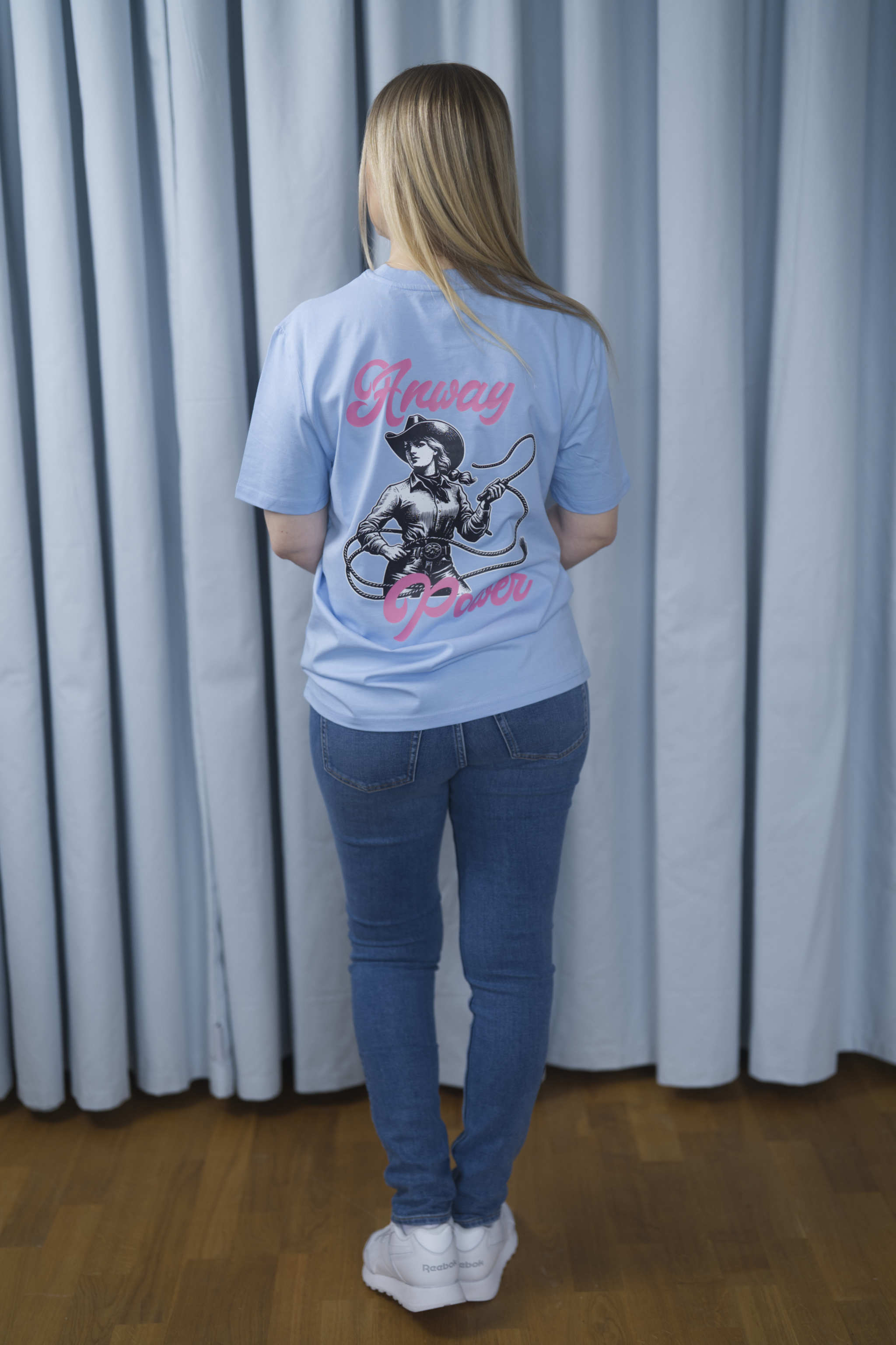 T-Shirt aus 100 % Bio-Baumwolle mit normaler Passform, erhältlich in verschiedenen Farben wie Blue Soul, Cotton Pink, Lavender, Aloe, Weiss und Schwarz. Individuell bedruckbar mit Wunschmotiv. Weiches, angenehm leichtes Material für hohen Tragekomfort. Ideal für einen zeitgemässen, entspannten Look. T-Shirt mit einer Cowgirl-Illustration mit Peitsche und dem rosa Schriftzug „Anway Power“ auf der Rückseite.