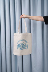 Naturfarbene Tote Bag mit türkis Aufdruck „EXPLORER GIRL“ – illustriert mit einem VW-Bus, Tannenbäumen und Bergen – robustes, stylisches Accessoire aus 80% recycelter Baumwolle und 20% recyceltem Polyester, fair produziert.