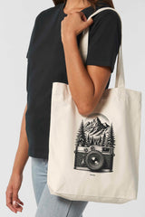Naturfarbene Tote Bag mit schwarzem Vintage-Motiv einer analogen, alten Kamera vor einem Bergpanorama und Tannen – hochwertige Stofftasche aus 80% recycelter Baumwolle und 20% recyceltem Polyester, ideal für Natur- und Fotografie-Liebhaber.