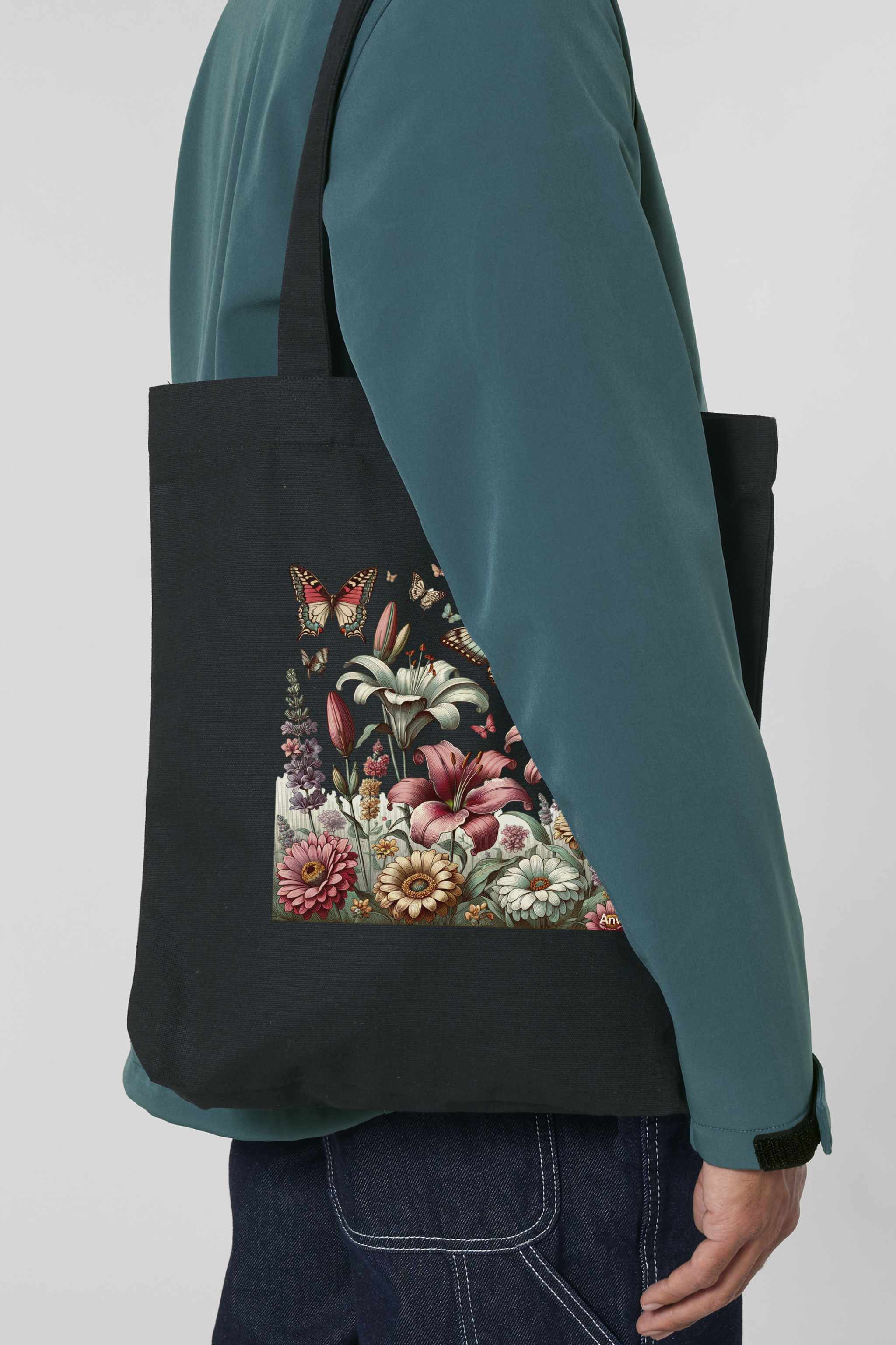 Schwarze Tote Bag mit farbiger Blumenwiese und Schmetterlingen – stilvoller, nachhaltiger Stoffbeutel aus 80% recycelter Baumwolle und 20% recyceltem Polyester, mit robusten Nähten und langen Henkeln.