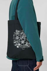 Schwarze Tote Bag mit weissem floralen Lineart-Motiv und kleinem „Anway“-Schriftzug – nachhaltige Tasche aus 80% recycelter Baumwolle und 20% recyceltem Polyester mit langen Henkeln und geräumigem Schnitt.
