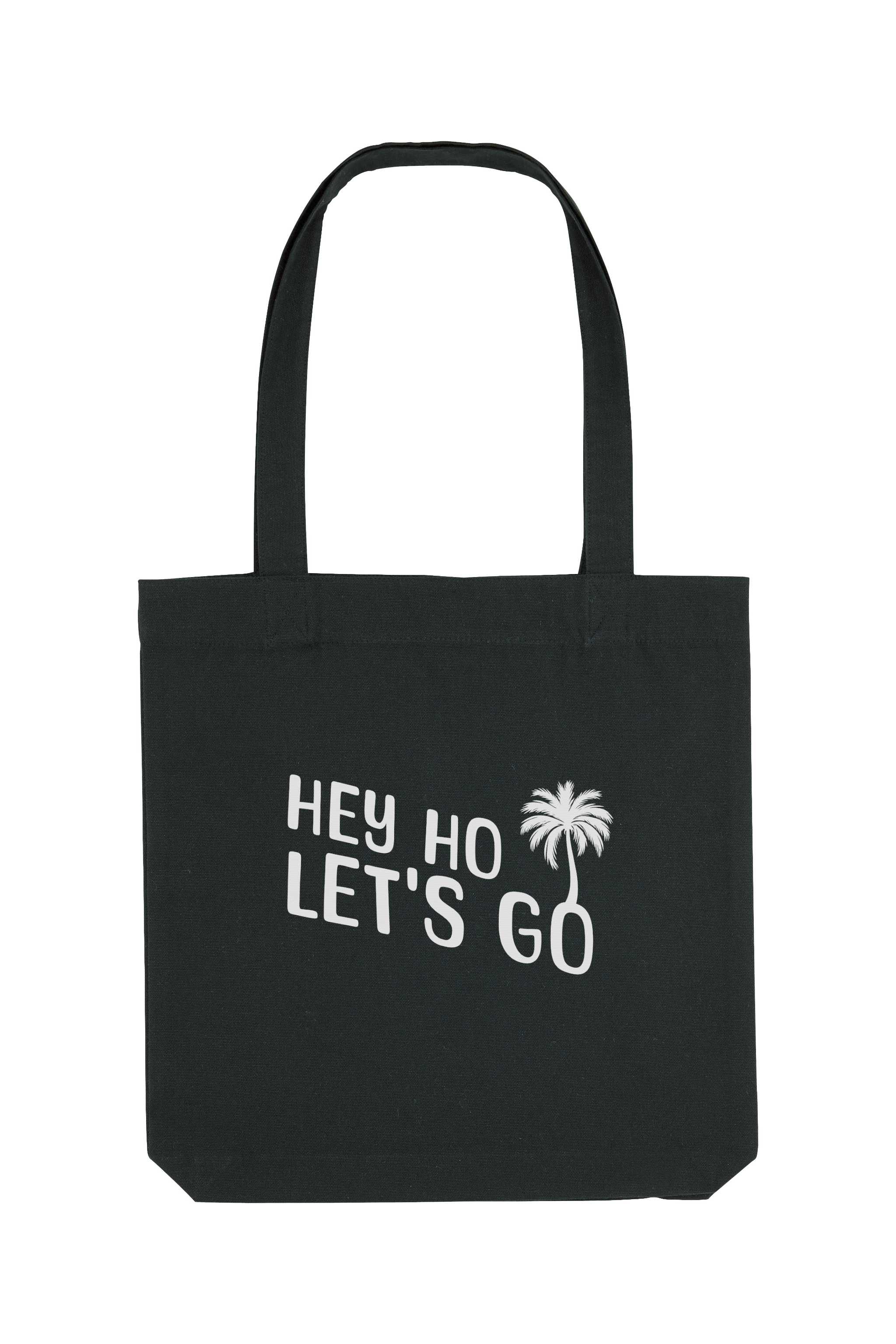 Schwarze Tote Bag mit weissem Schriftzug „HEY HO LET’S GO“ und Palmenmotiv – nachhaltige Stofftasche aus recycelten Materialien mit langen Henkeln und geräumigem Schnitt.