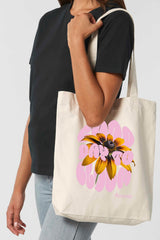 Naturfarbene Tote Bag mit dem rosa Schriftzug „GOOD DAY TO BLOOM“ im Retro-Stil, durchzogen von einer leuchtend gelben Sonnenblume – florales Statement-Piece mit positiver Botschaft.